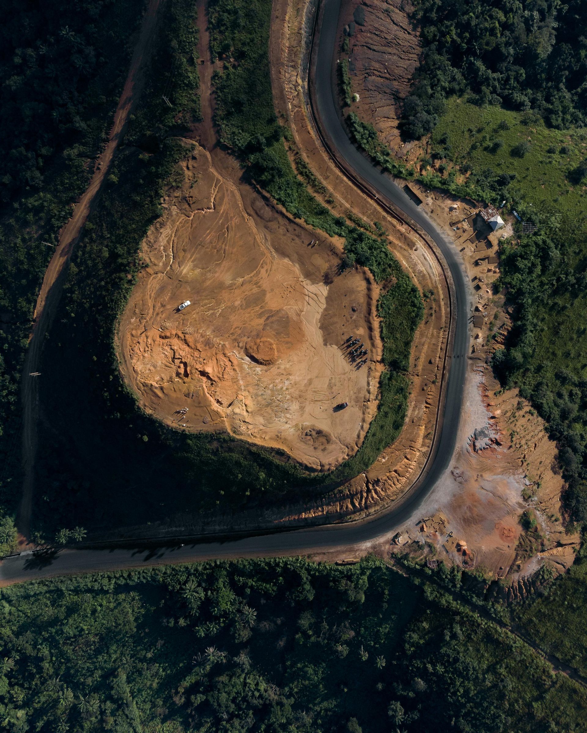 An aerial view of a road going through a forest.