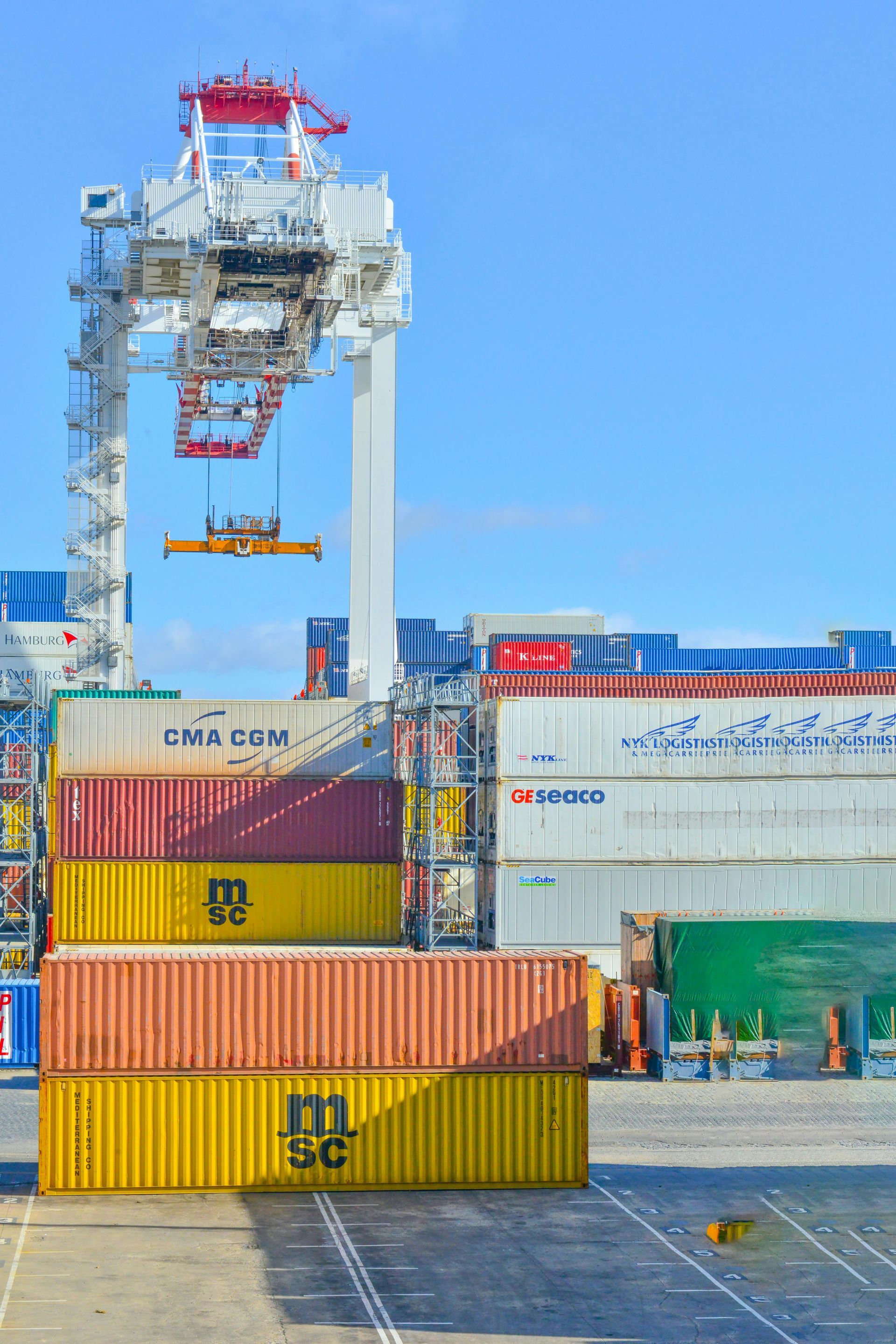 A crane is lifting a stack of shipping containers in a harbor.