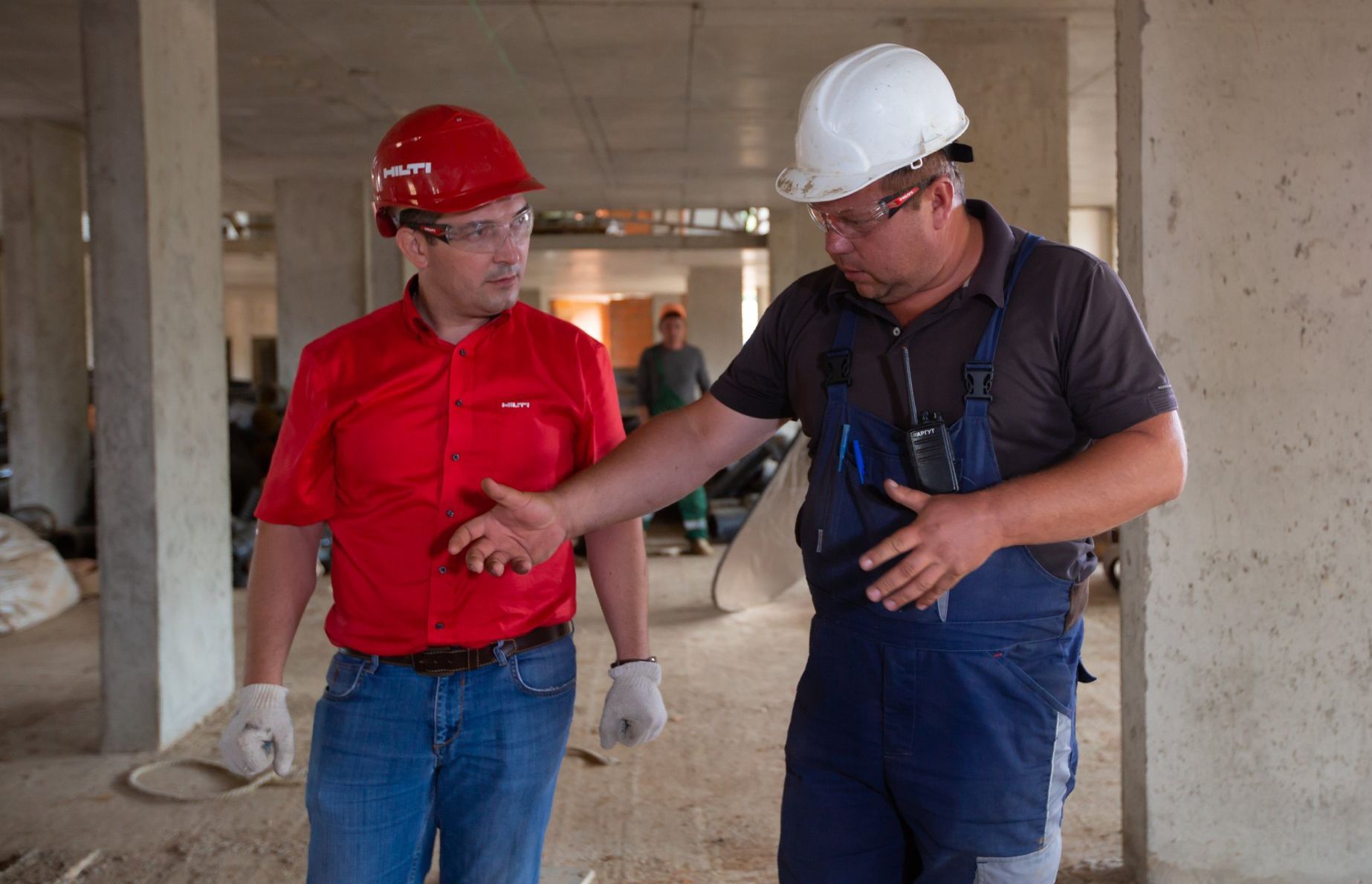 Two construction workers are talking to each other in a building under construction.