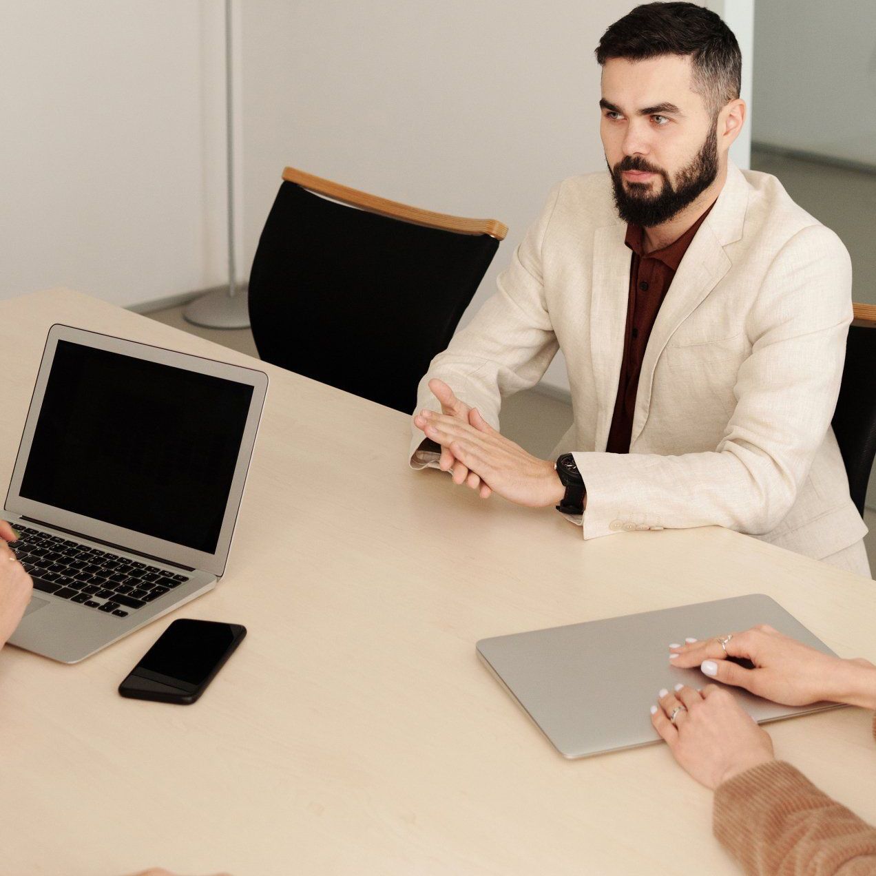 A man with a beard sits at a table with a laptop