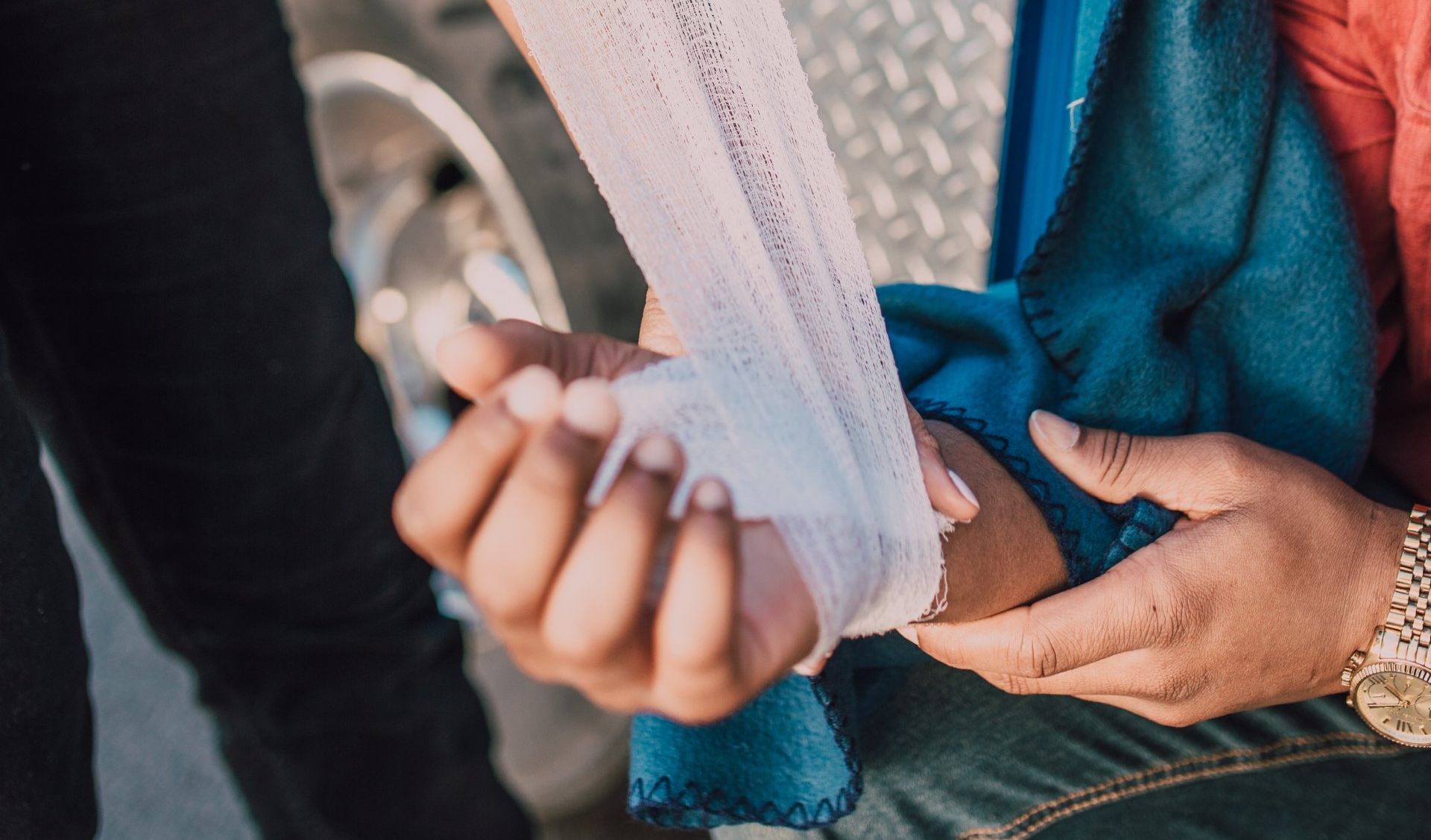 A person is wrapping another person 's hand with a bandage.