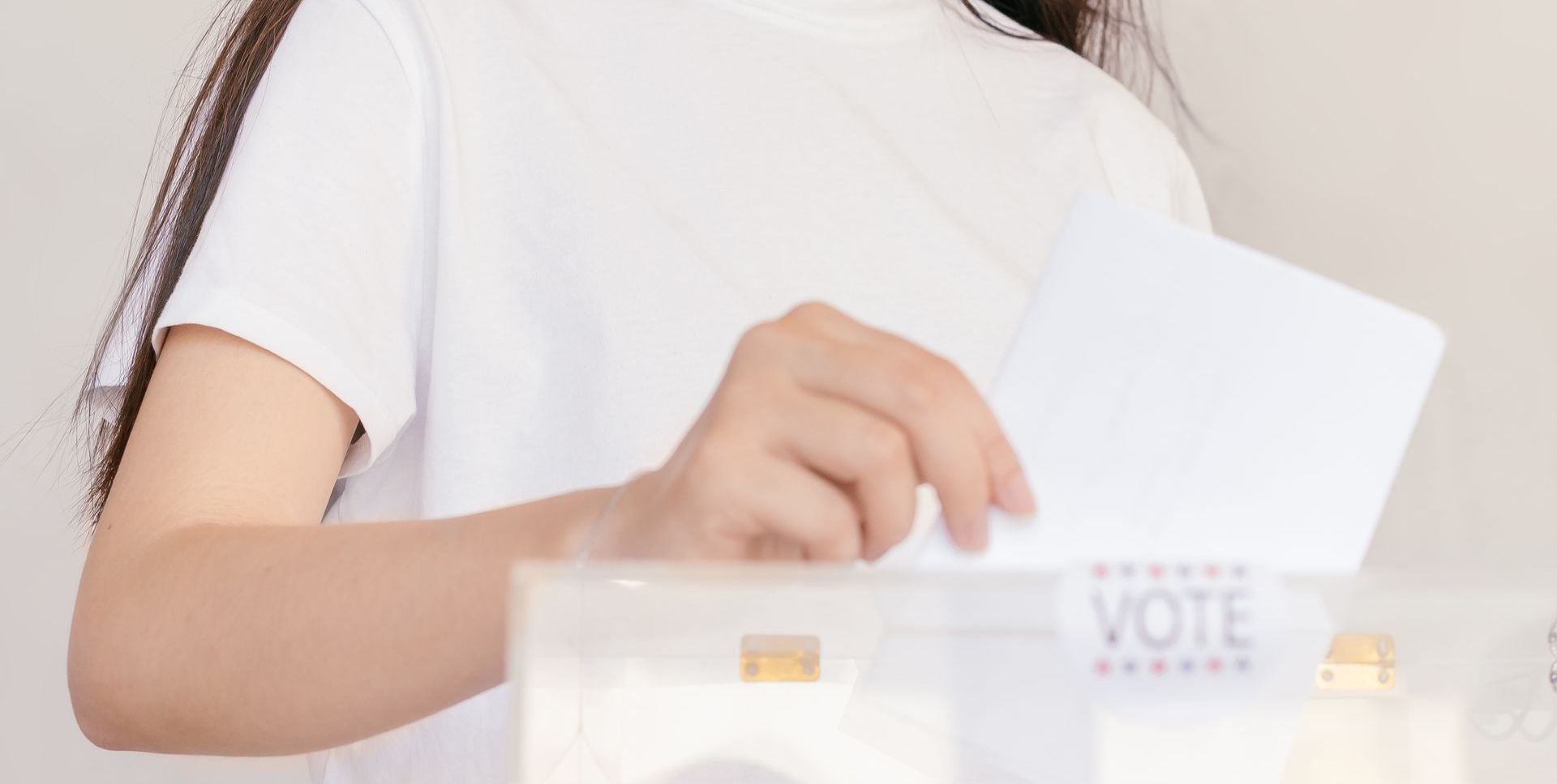 A woman is putting a ballot in a ballot box.