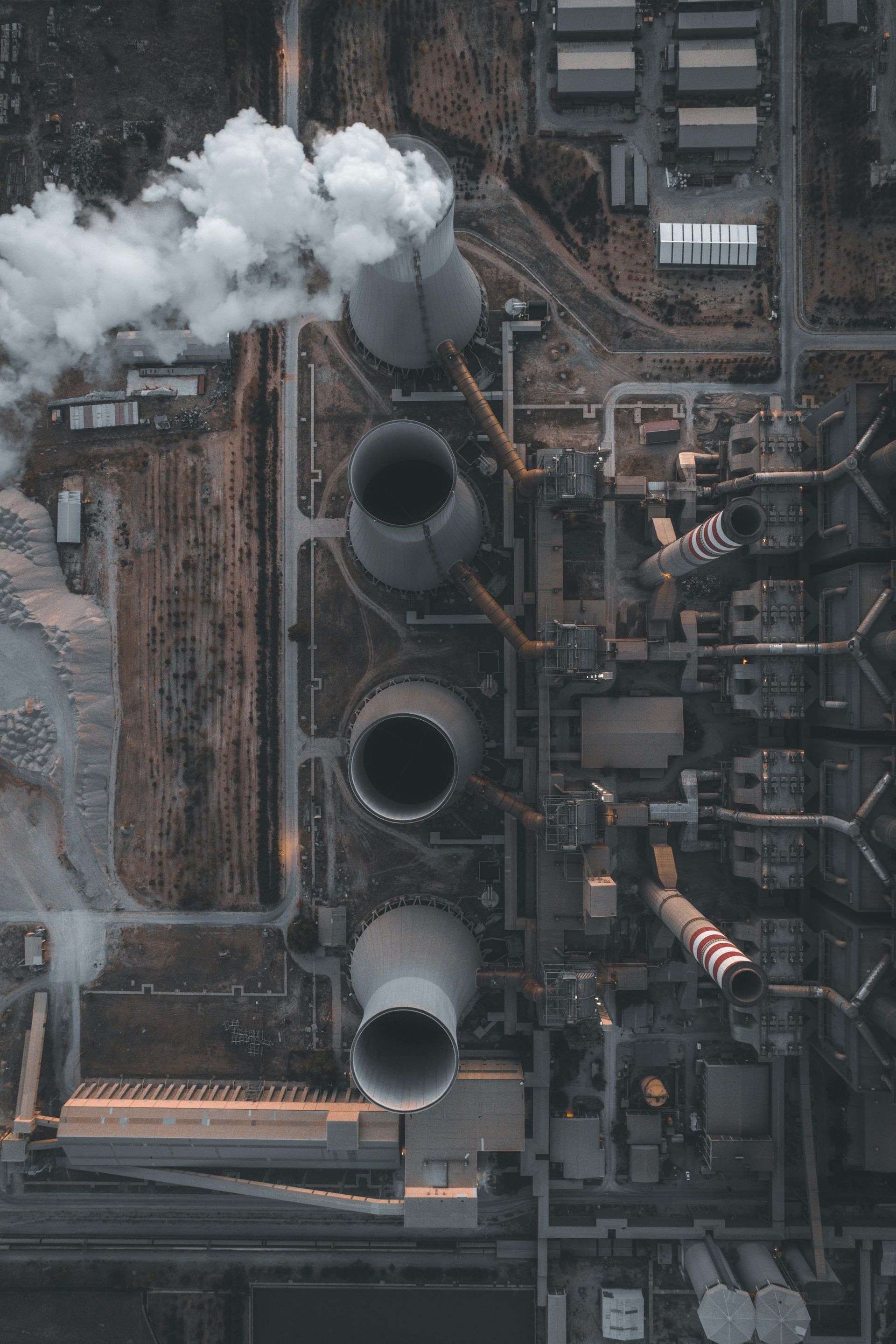 An aerial view of a power plant with smoke coming out of the chimneys.