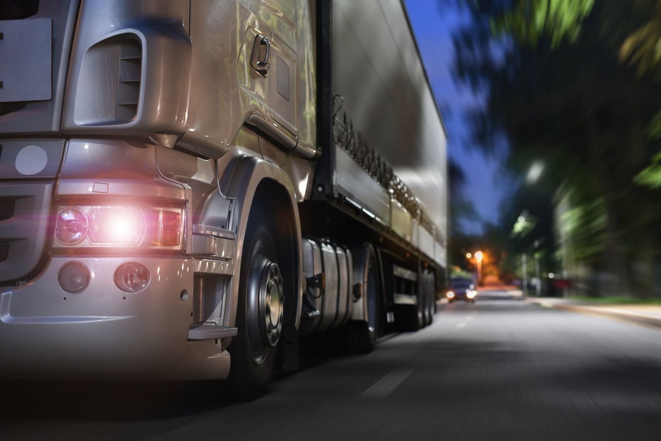 A semi truck is driving down a city street at night.