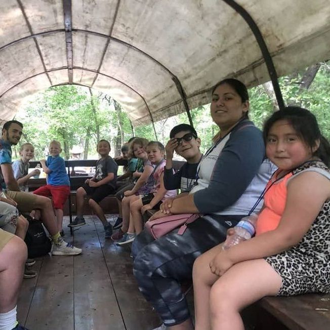 A group of people are sitting in a covered wagon.