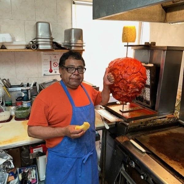 A man in an apron is holding a large piece of meat