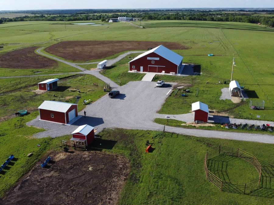 An aerial view of a farm with red barns and a field.