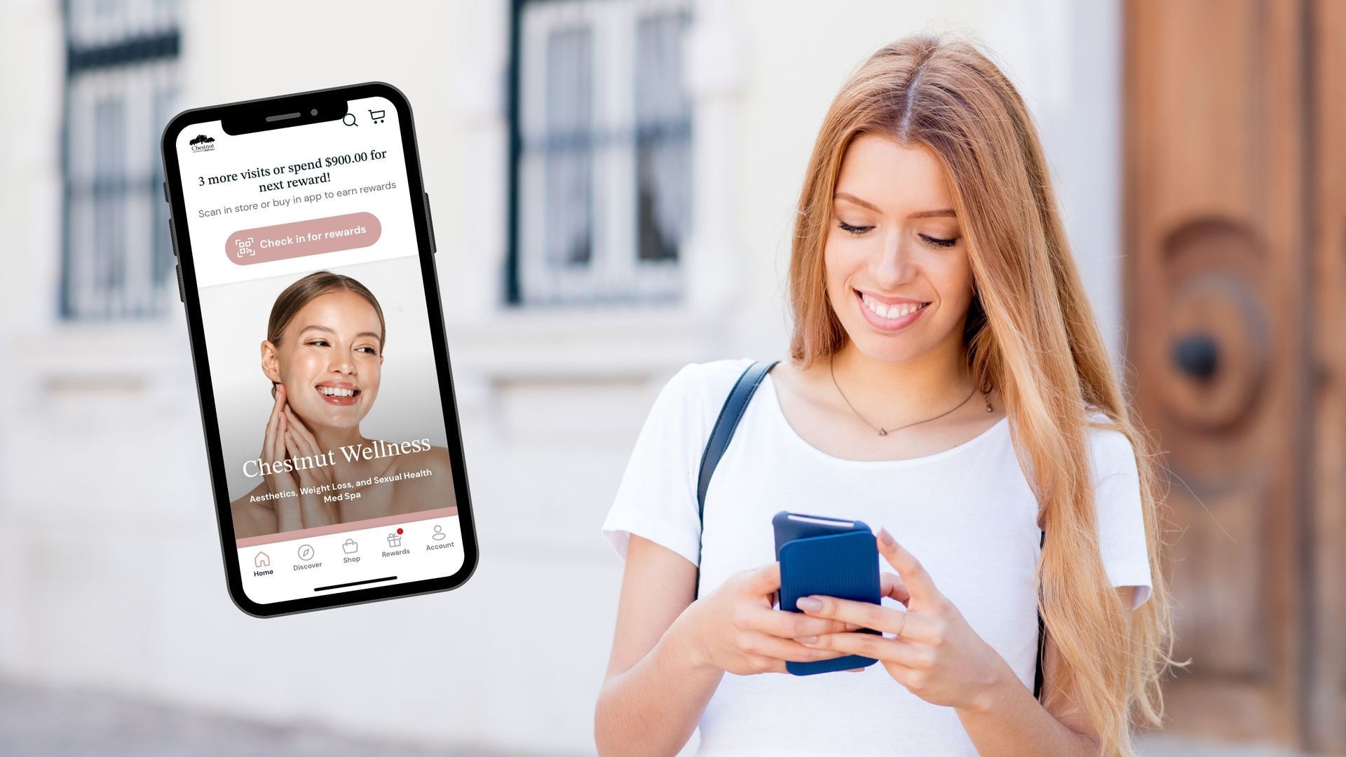 A woman is smiling while looking at her cell phone.