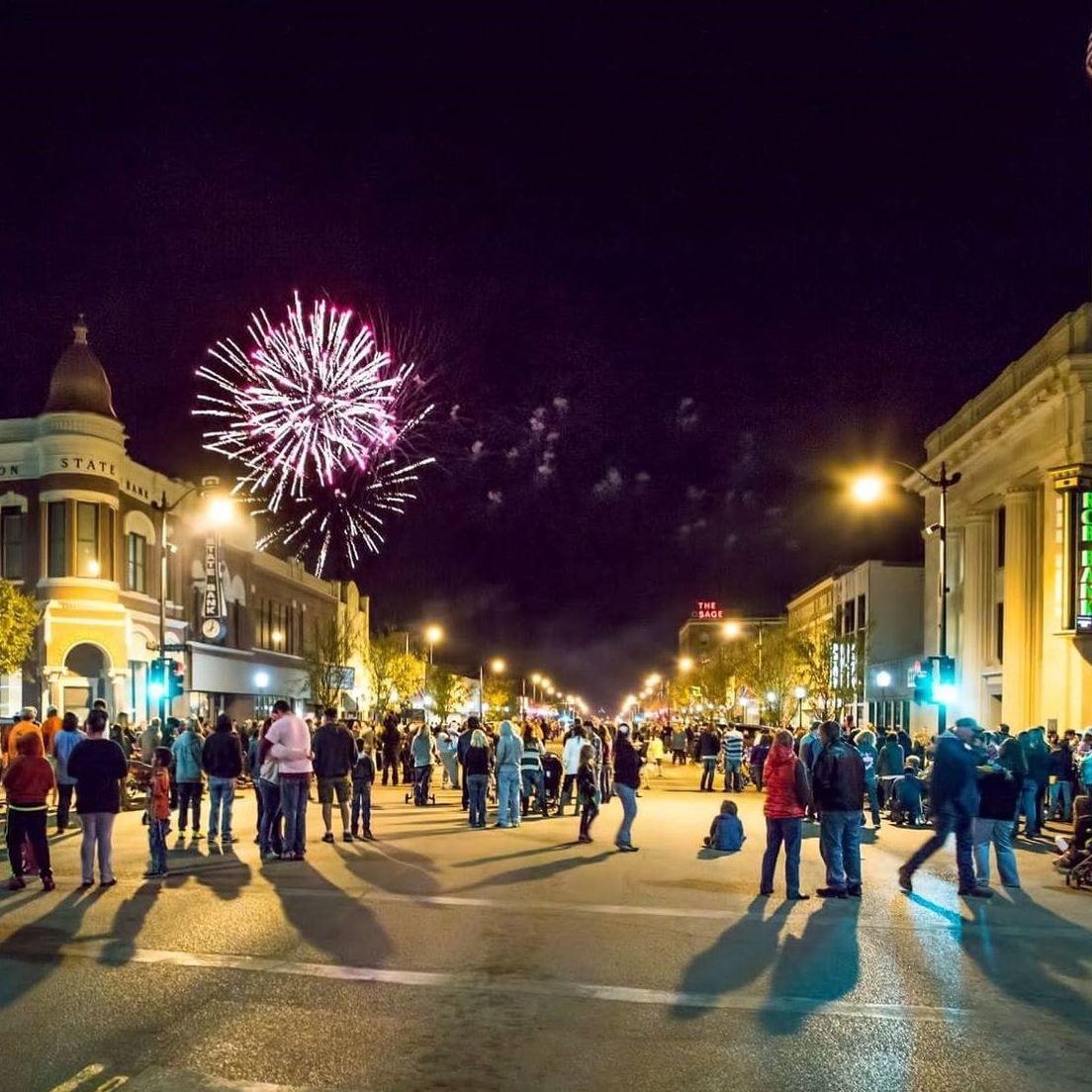 A group of people at a downtown festival at night.