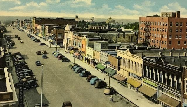 Ark City Downtown Post Card An aerial view of a city street with cars parked on the sidewalk