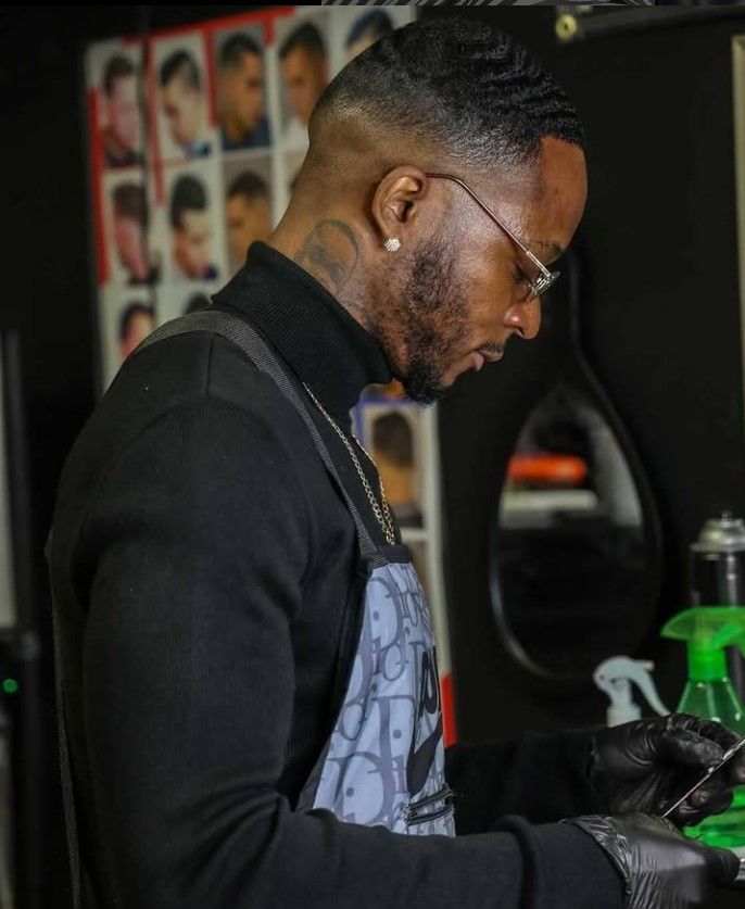 A man is cutting a man 's hair in a barber shop.