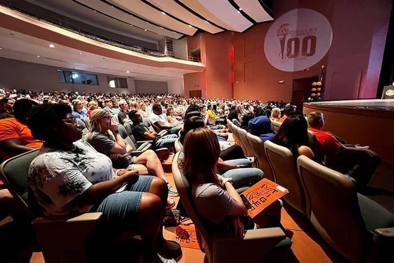 A large group of people are sitting in an auditorium watching a presentation.