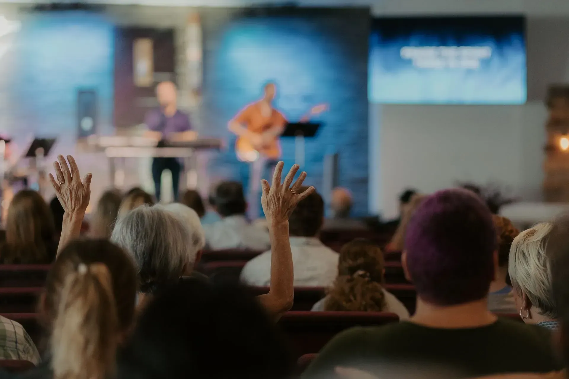 A crowd of people are raising their hands in a church.