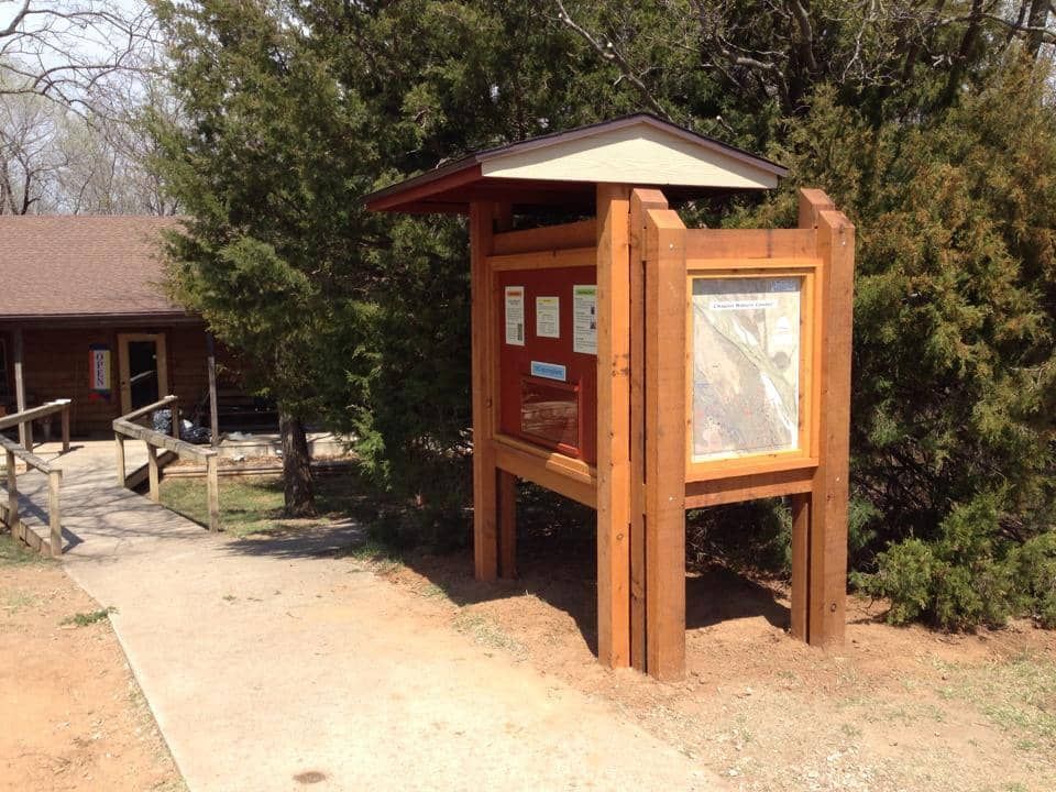 A wooden kiosk with a trail map on it in front of a building