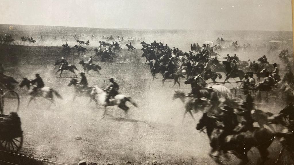 A black and white photo of a herd of horses in a field.