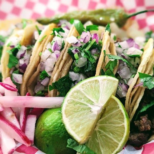 A close up of a taco with limes and onions