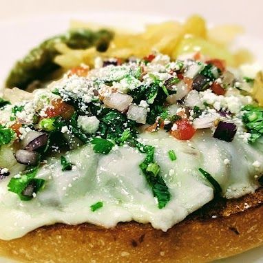 A close up of a sandwich with cheese and vegetables on a plate.
