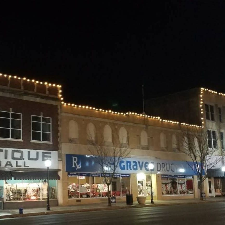 A row of stores including the antique mall are lit up at night