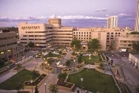 Exterior view of a large hospital complex at dusk, with a central courtyard and surrounding city buildings.