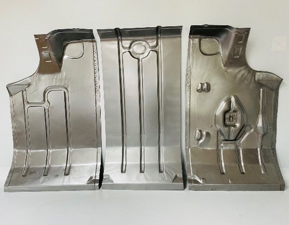 Three pressed metal car floor panels laid out, showing interior structure. They are light silver and arranged side-by-side.