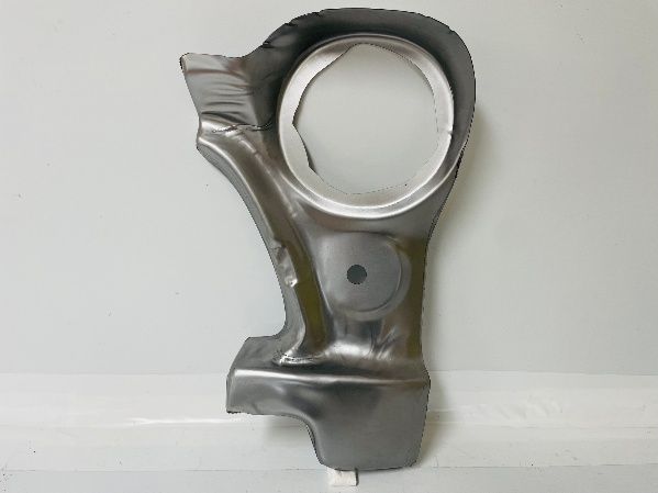 Silver metal car part with a large hole, possibly a section of a connecting rod or suspension component, on a white surface.