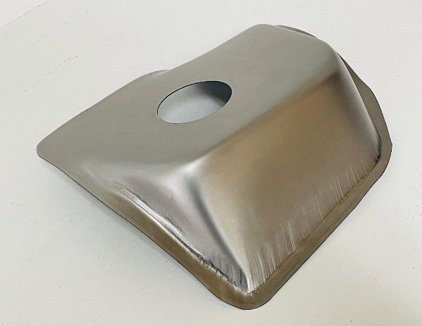 A shiny, metal, square-shaped automotive floor pan with a round hole in the center.