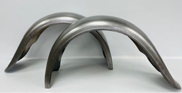 A pair of metal fenders are sitting on top of each other on a white surface.