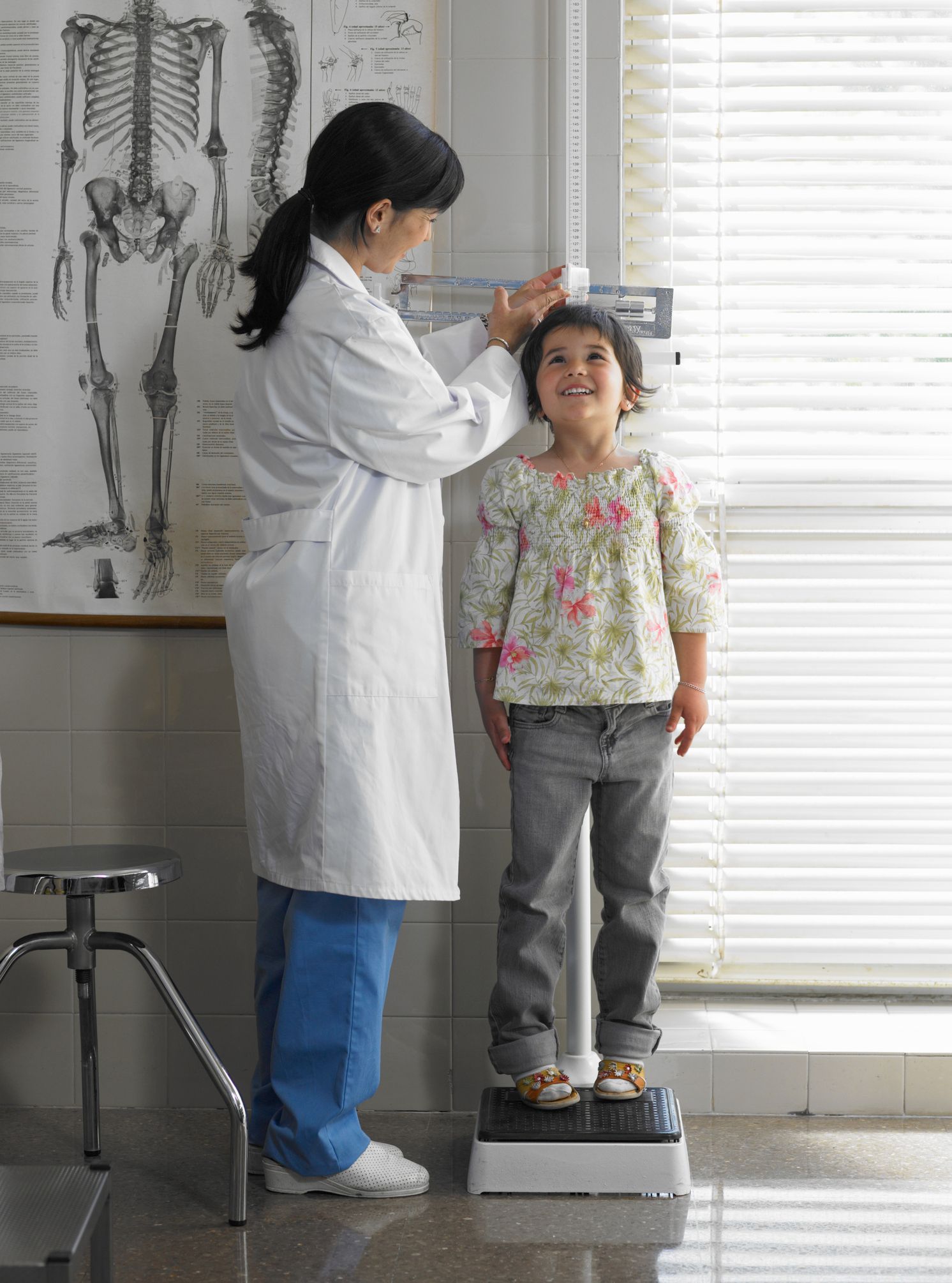 A doctor is measuring the height of a little girl