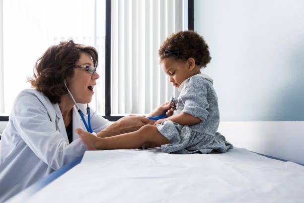 A doctor is listening to a little girl 's heartbeat with a stethoscope.
