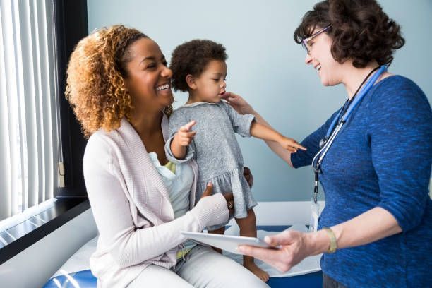 A woman is holding a child while talking to a doctor.