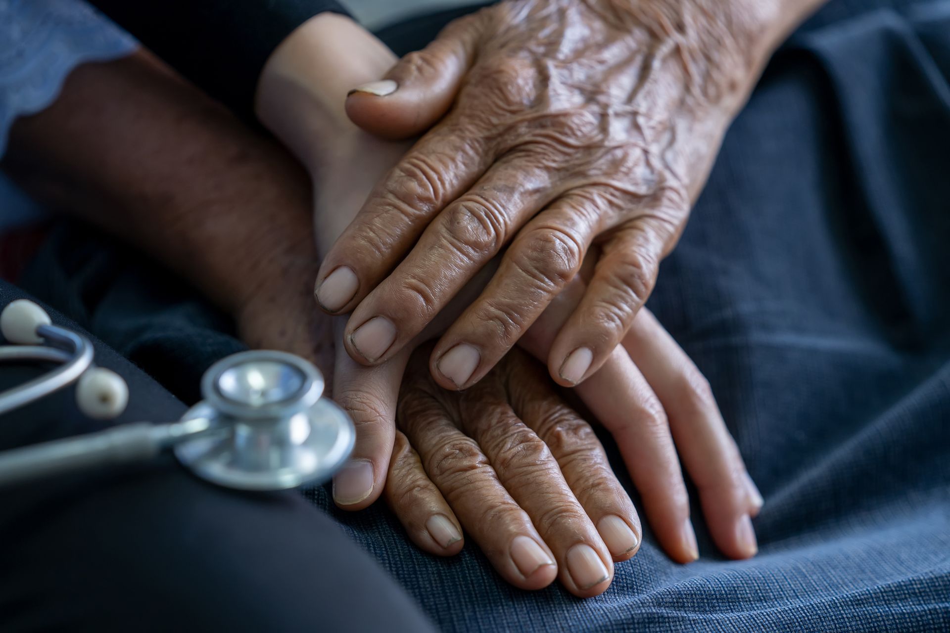 A doctor is holding the hands of an elderly woman.