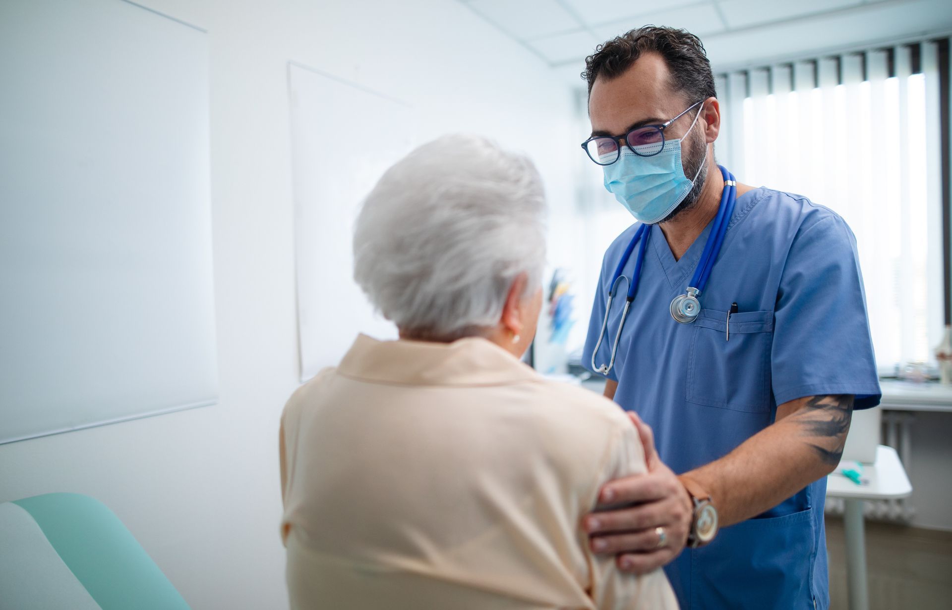 A doctor wearing a mask is talking to an elderly woman.