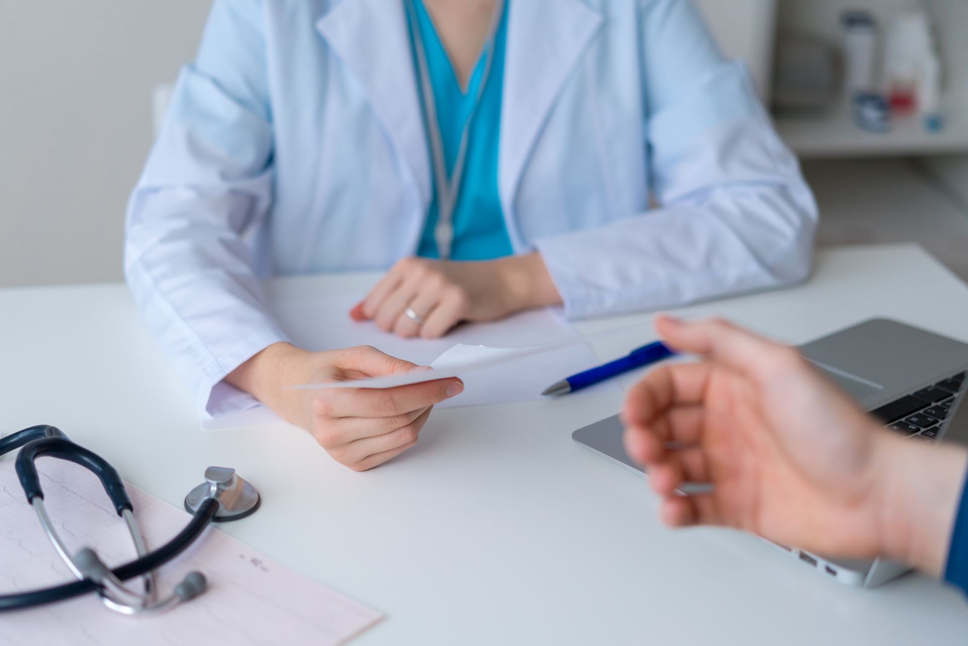A doctor is sitting at a desk talking to a patient.