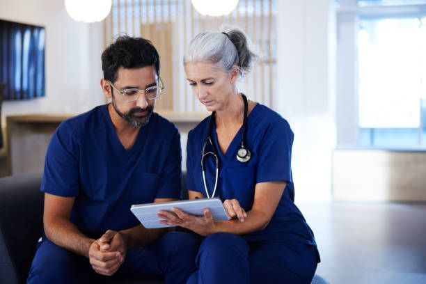 A man and a woman are sitting on a couch looking at a tablet.