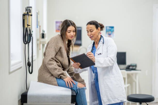 A doctor is talking to a patient who is sitting on an examination table.