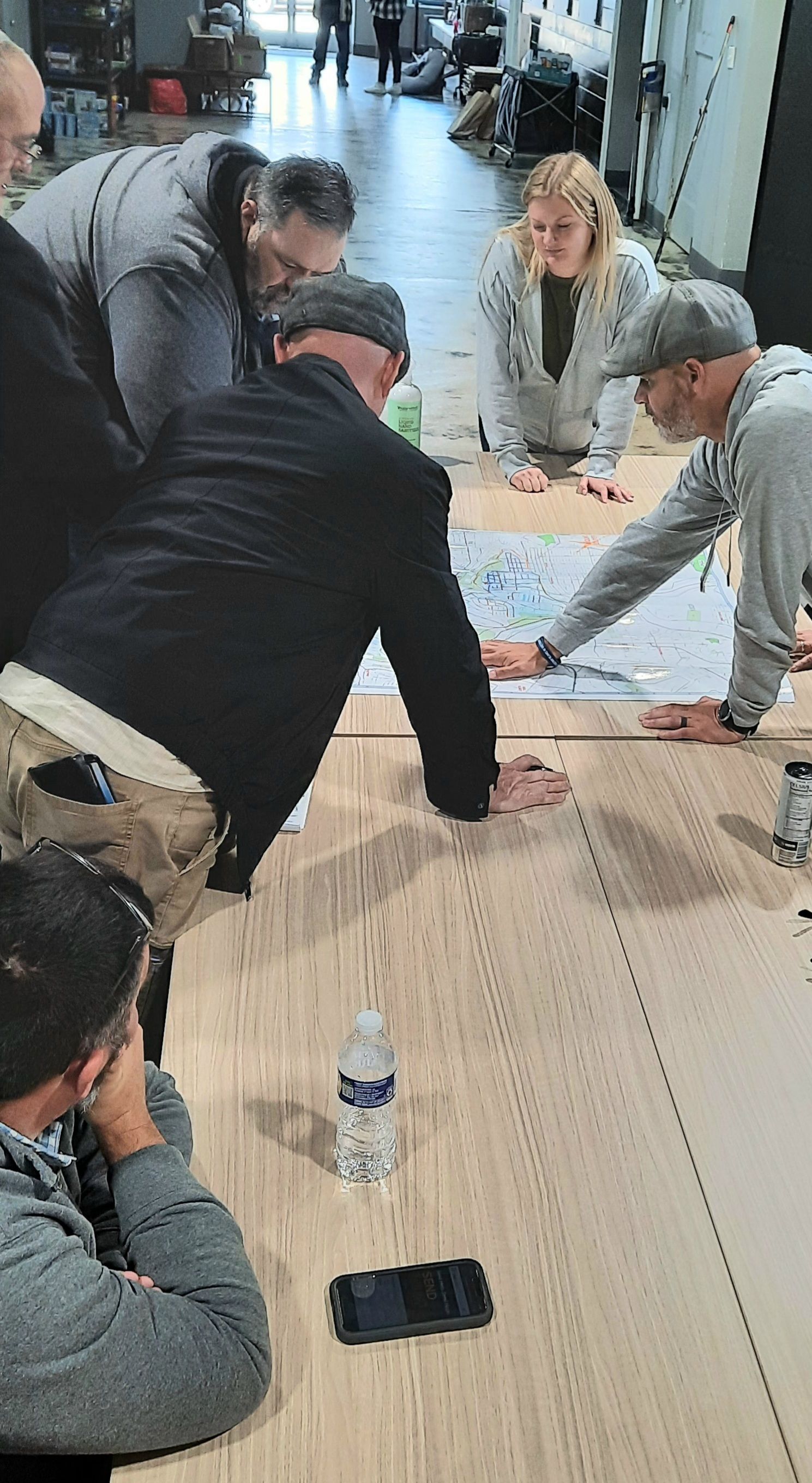 A group of people are sitting around a wooden table looking at a map.