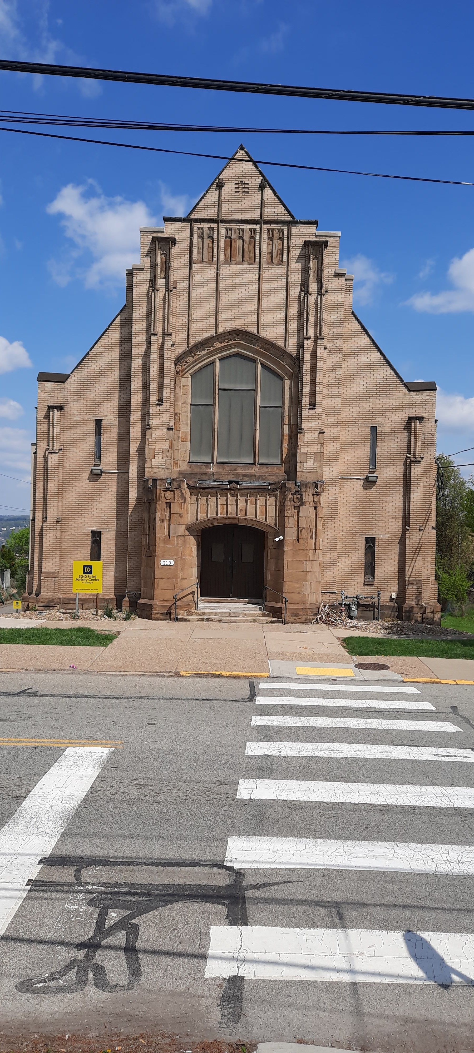An old church is sitting on the side of the road next to a crosswalk.