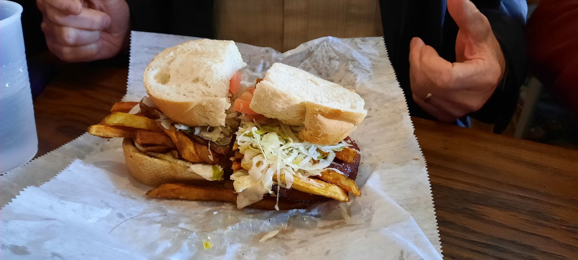A close up of a sandwich with french fries on a table.