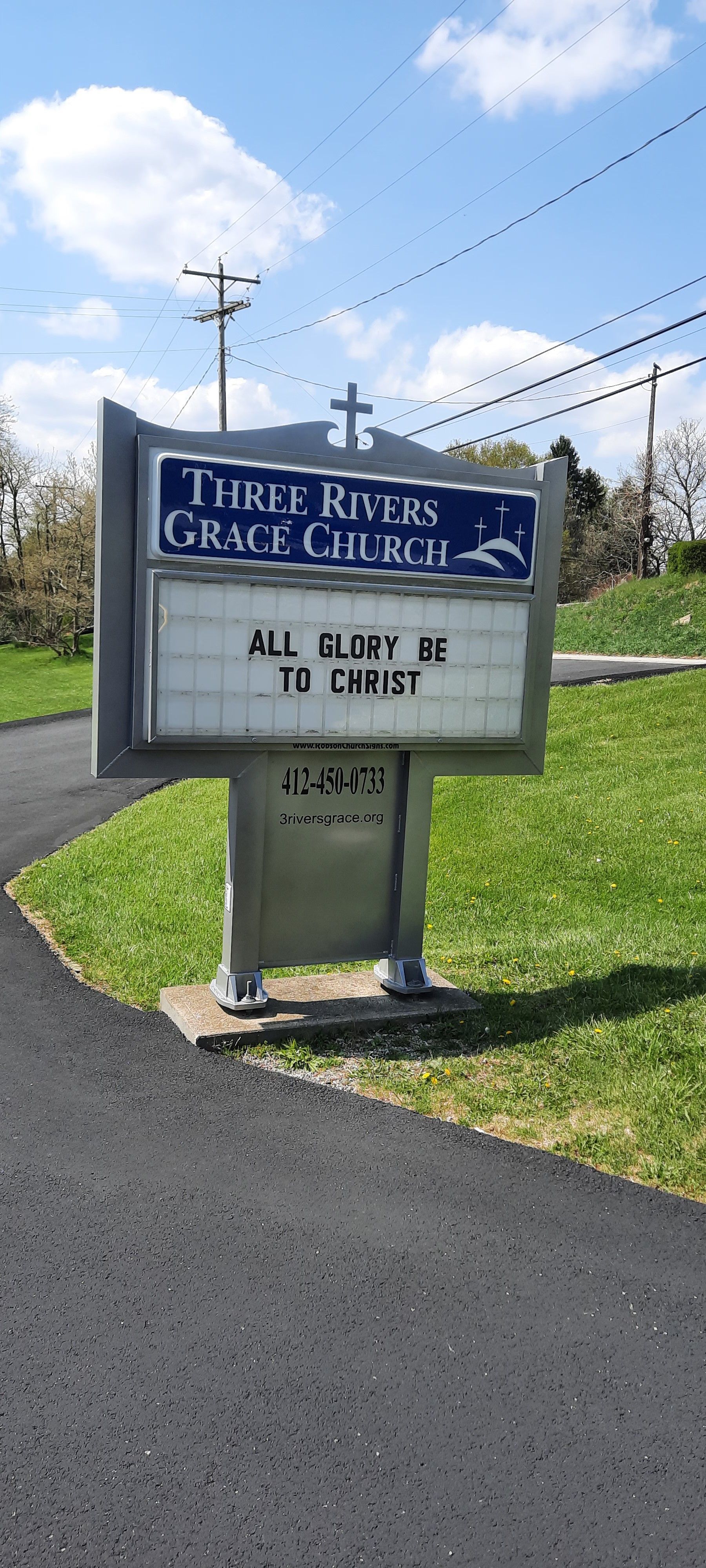 A church sign is sitting on the side of a road.