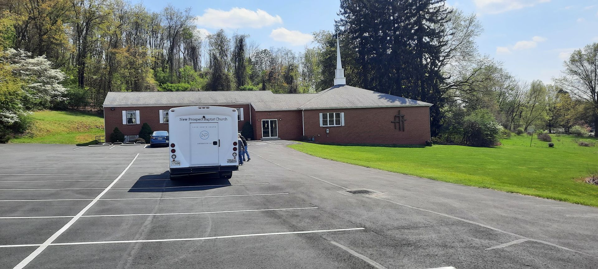 A white trailer is parked in a parking lot in front of a brick building.
