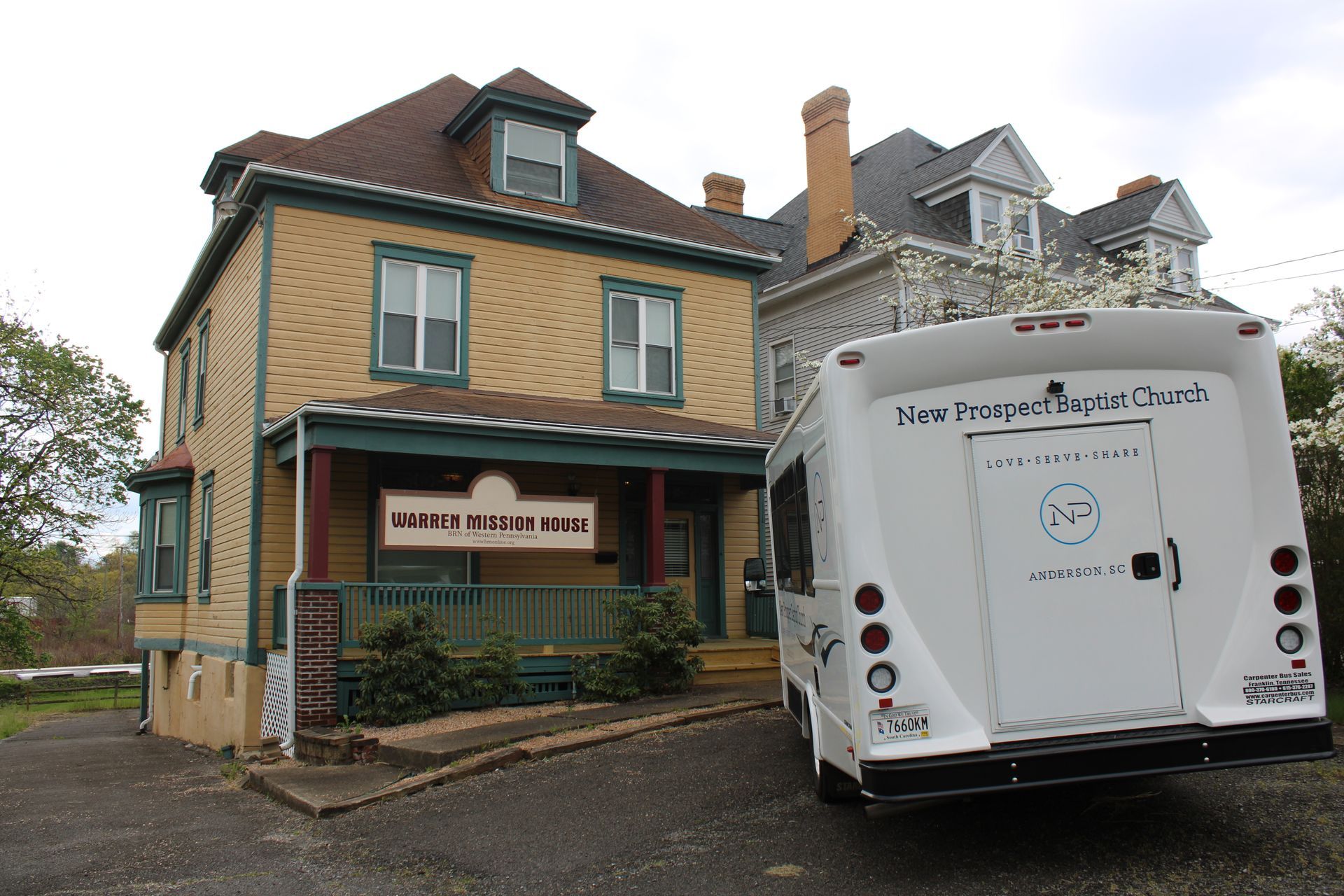 A white van is parked in front of a yellow house