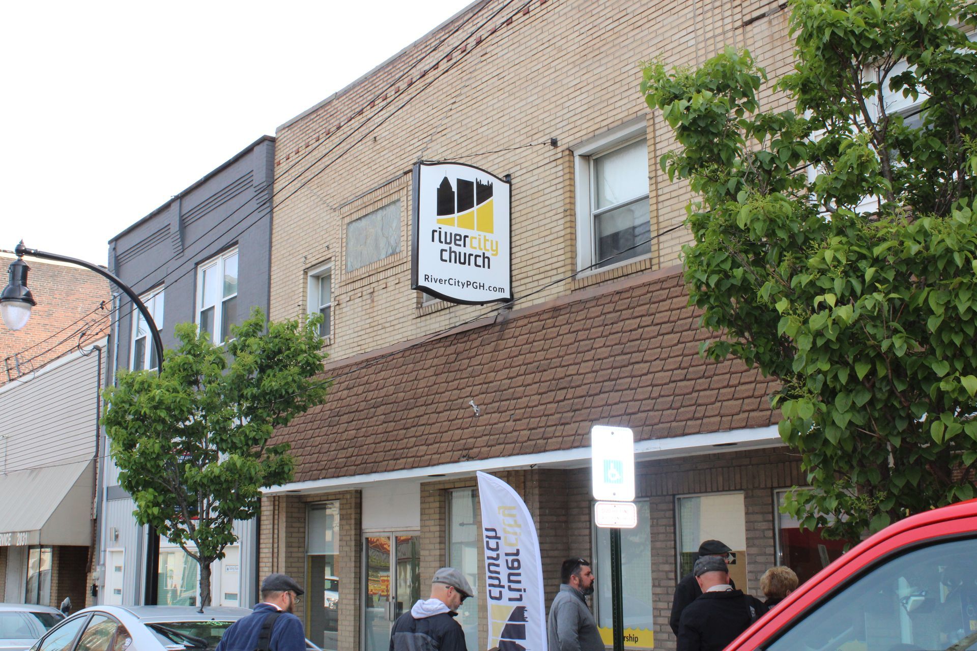 A group of people are standing outside of a building with a sign that says new club