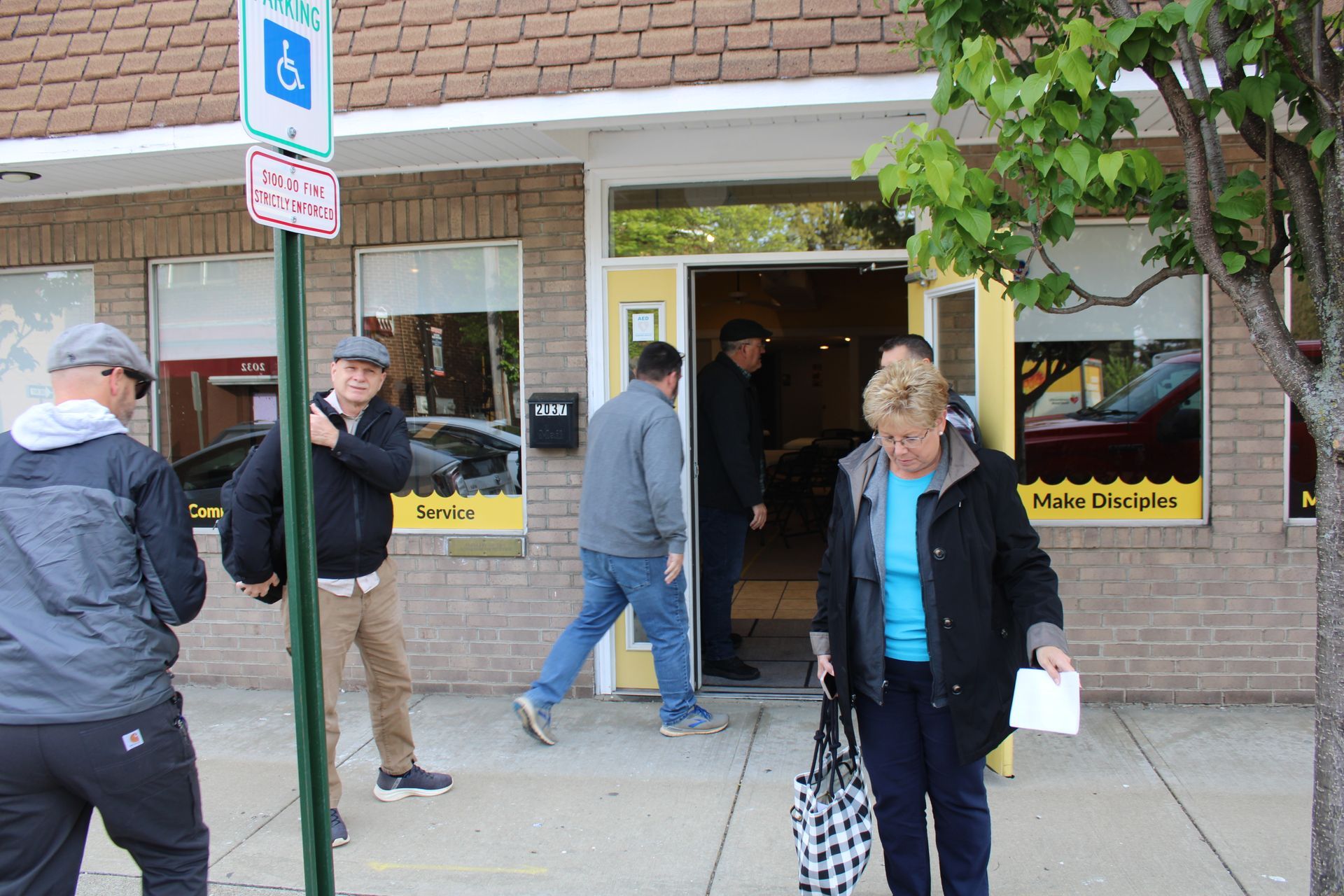 People walking in front of a building with a handicap sign