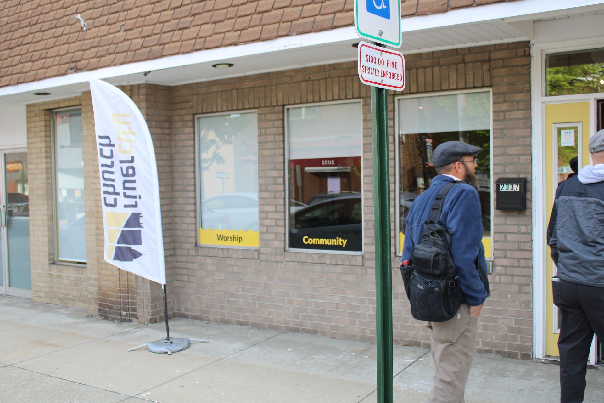 A man is standing on the sidewalk in front of a building.