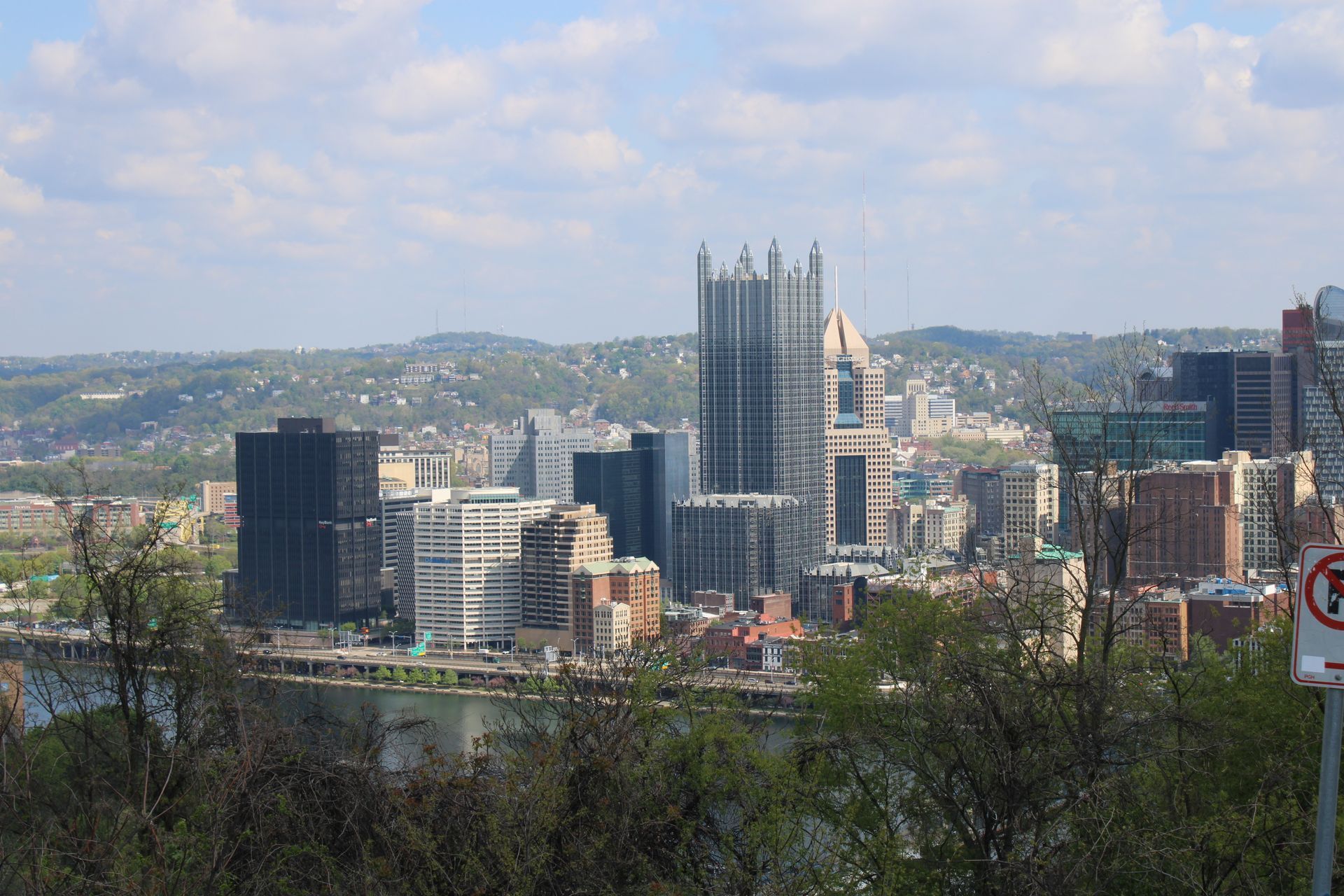 A city skyline with a no parking sign in the foreground