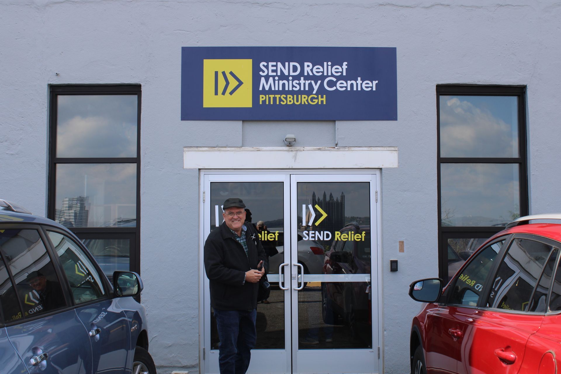 A man is standing in front of a building that says send relief ministry center.