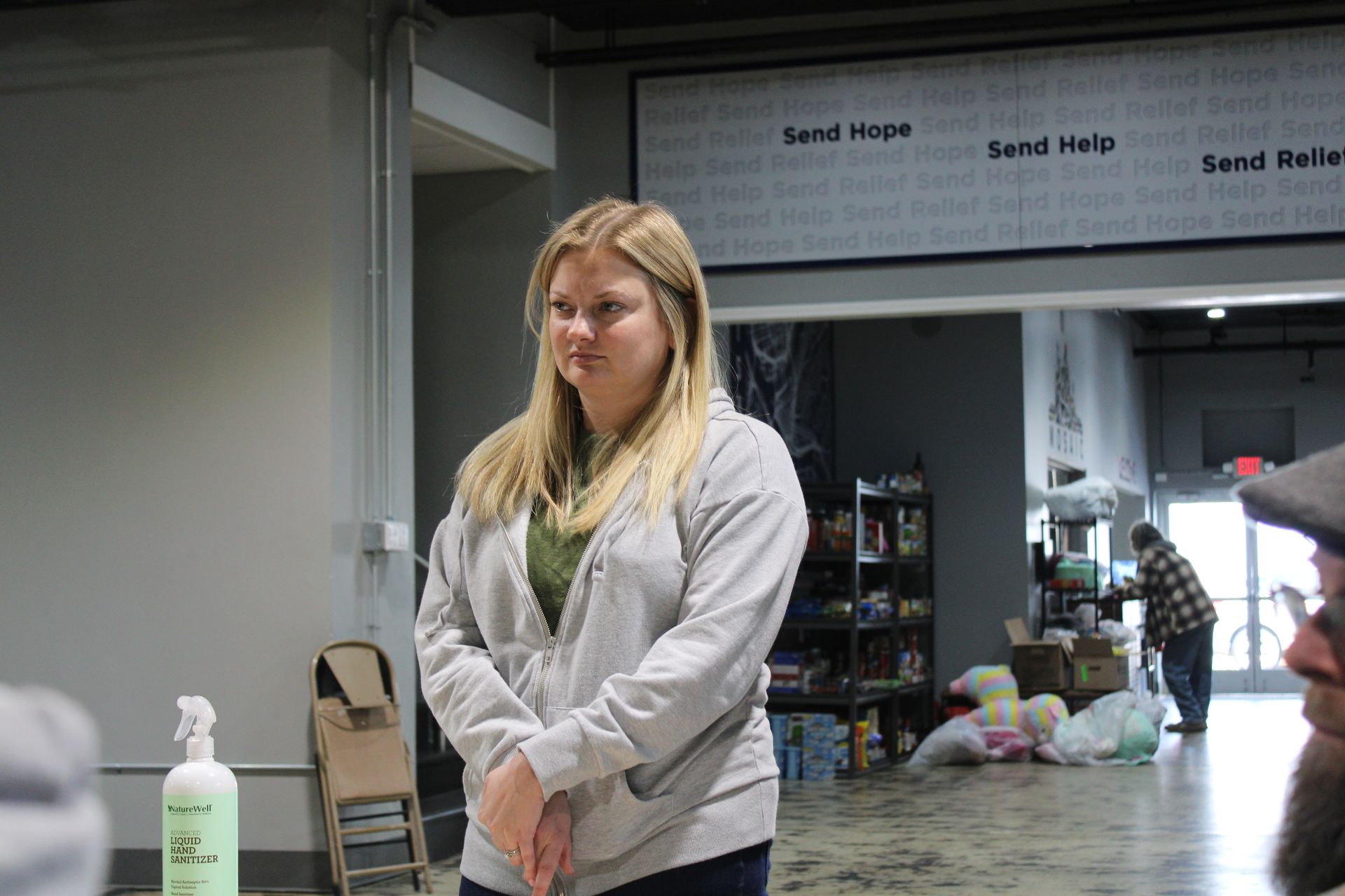 A woman is standing in a room with a spray bottle in front of her.