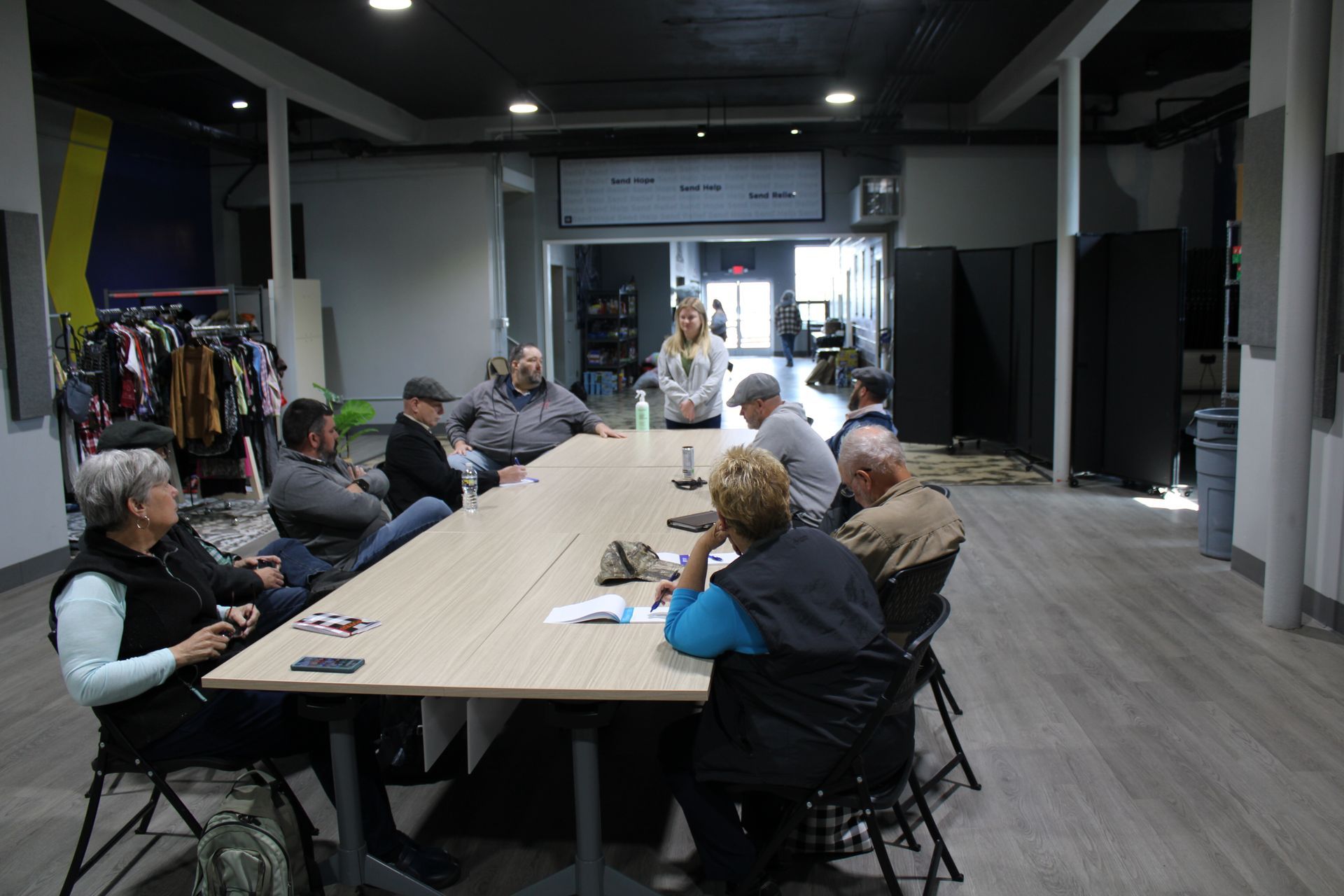 A group of people are sitting around a long table in a room.