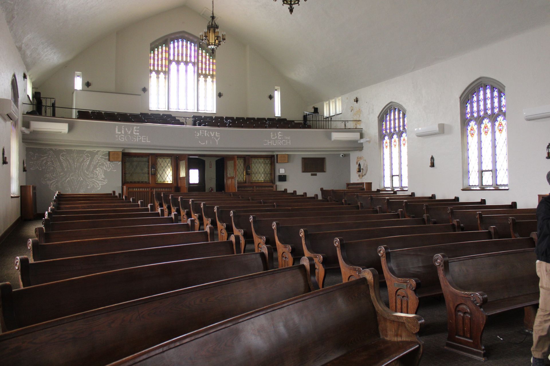 An empty church with rows of wooden benches and stained glass windows