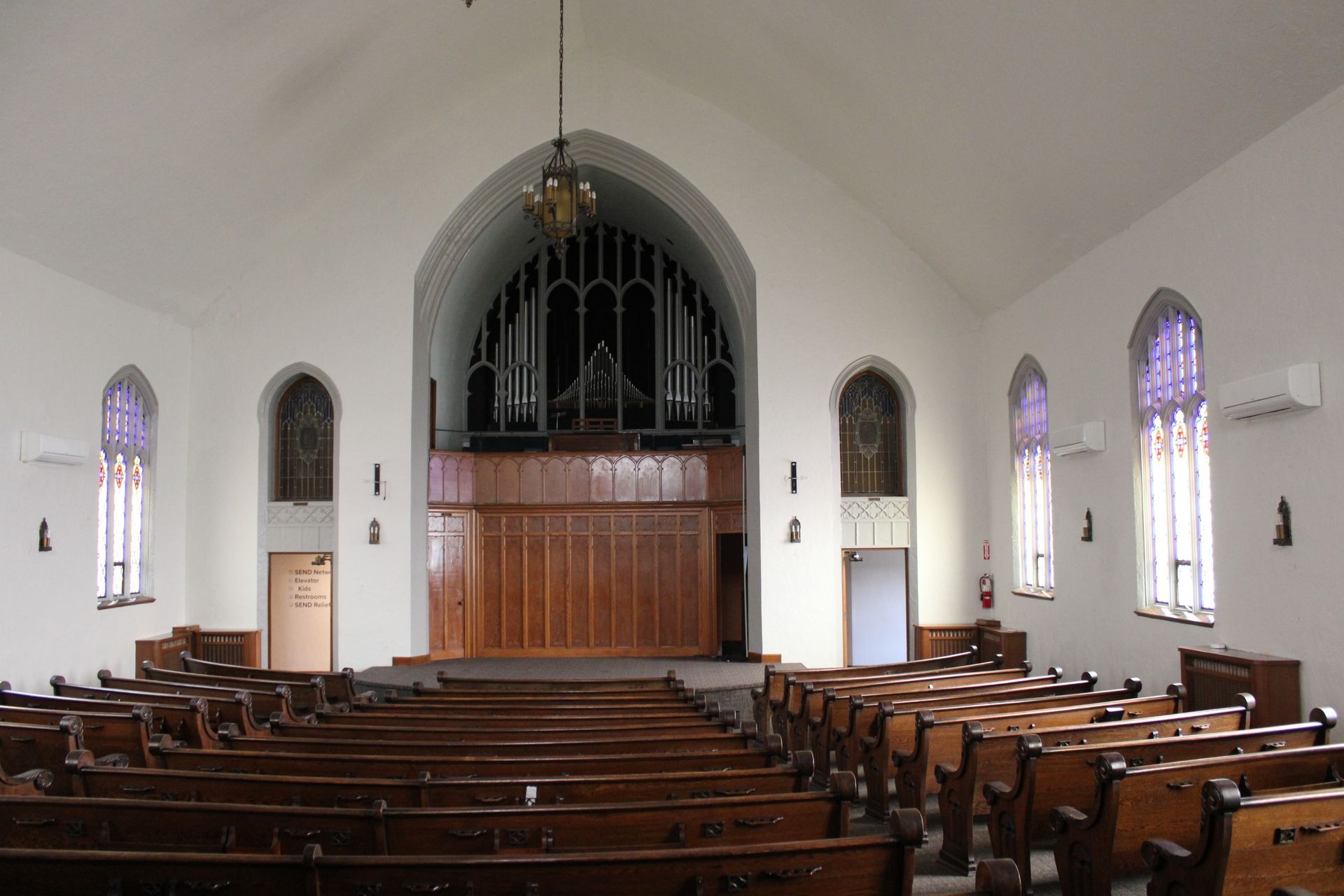 An empty church with rows of wooden benches and stained glass windows